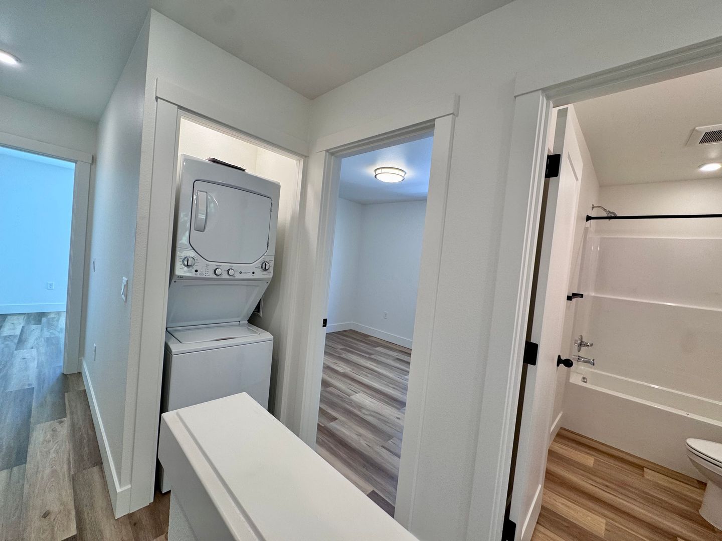 Upstairs hallway with in-unit laundry closet and full bathroom with tub