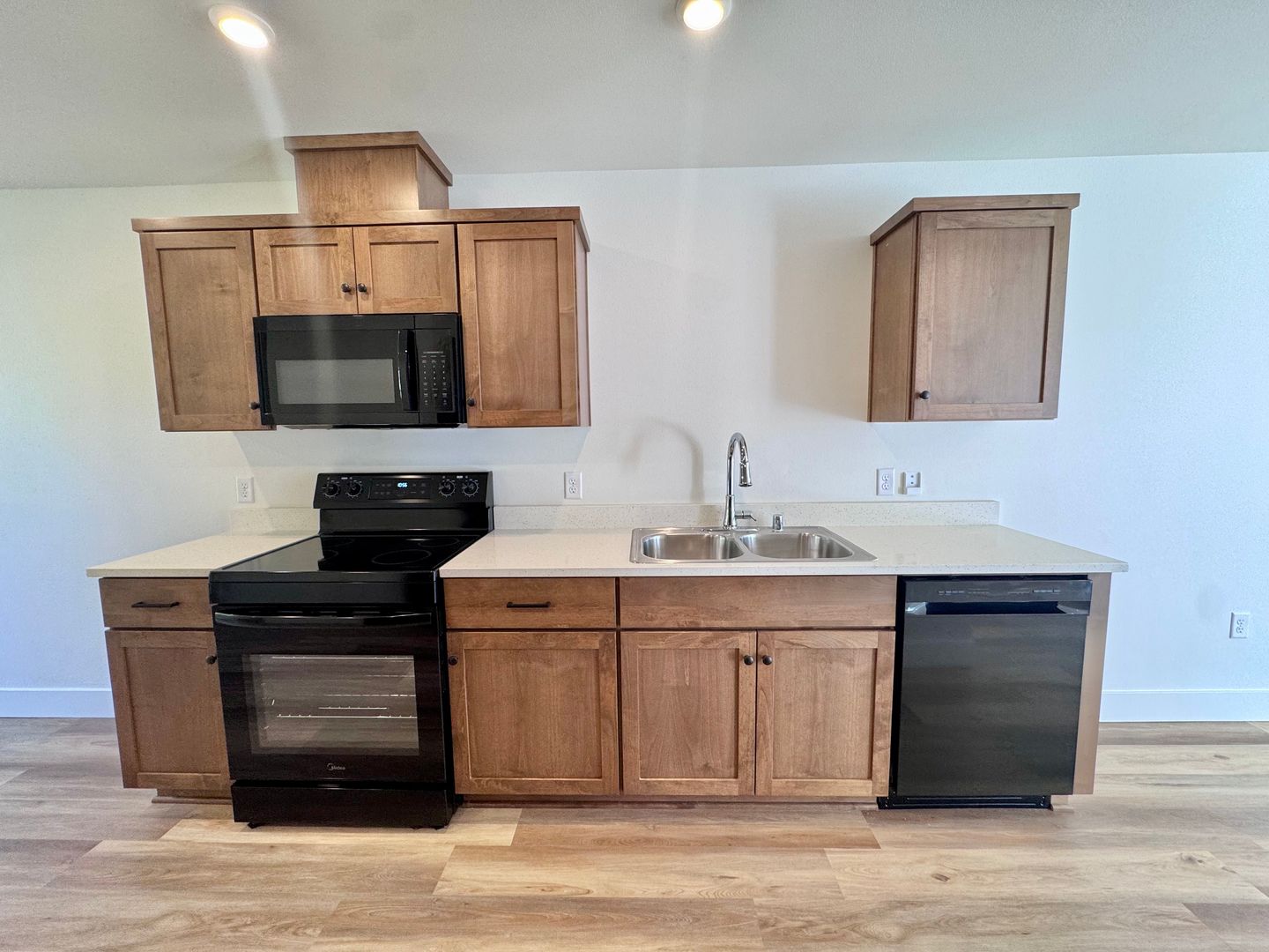 Kitchen with shaker-style wood cabinets, black appliances, and quartz-look countertops
