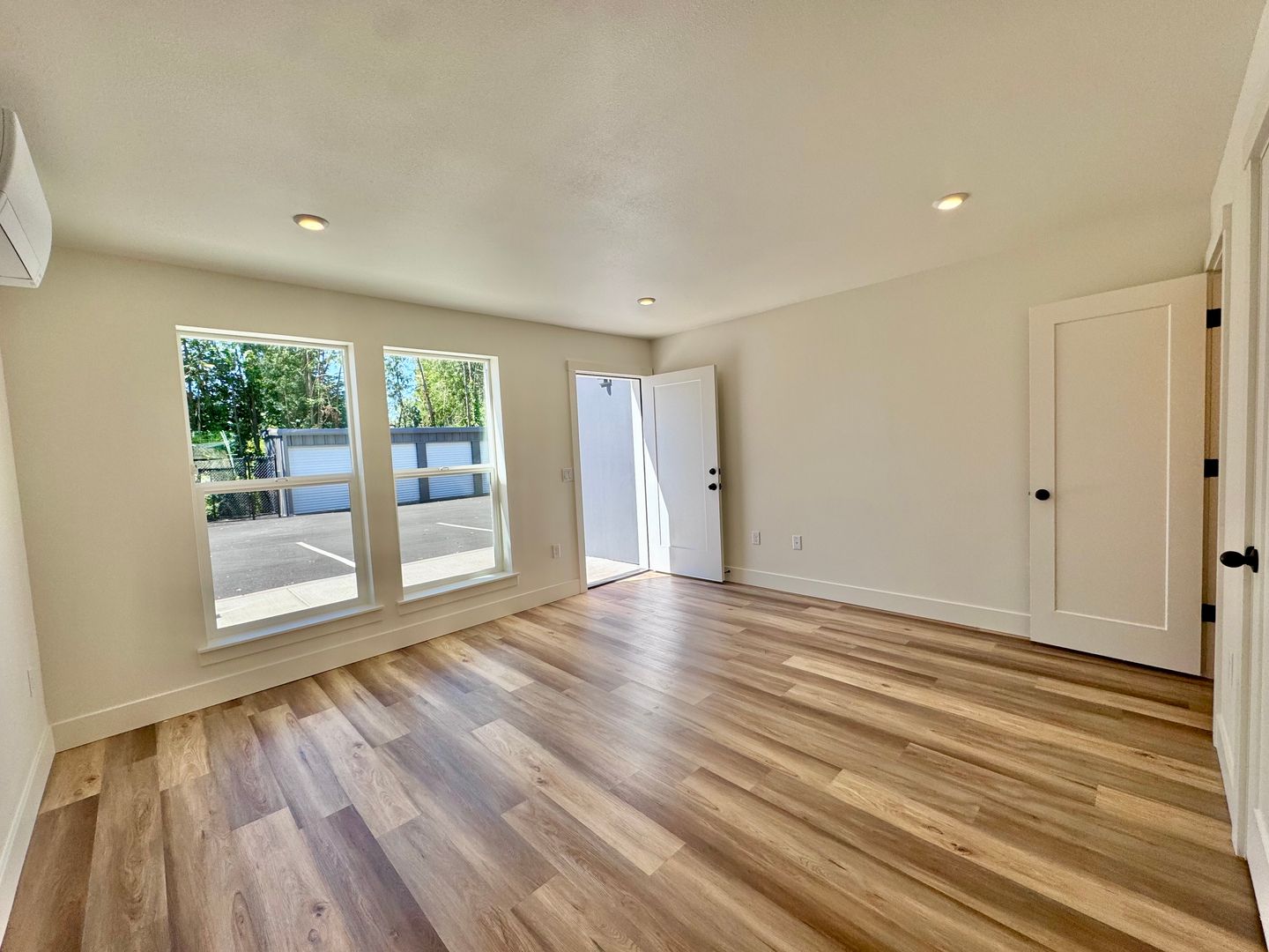 Bright open living room with vinyl plank flooring and a private entry door